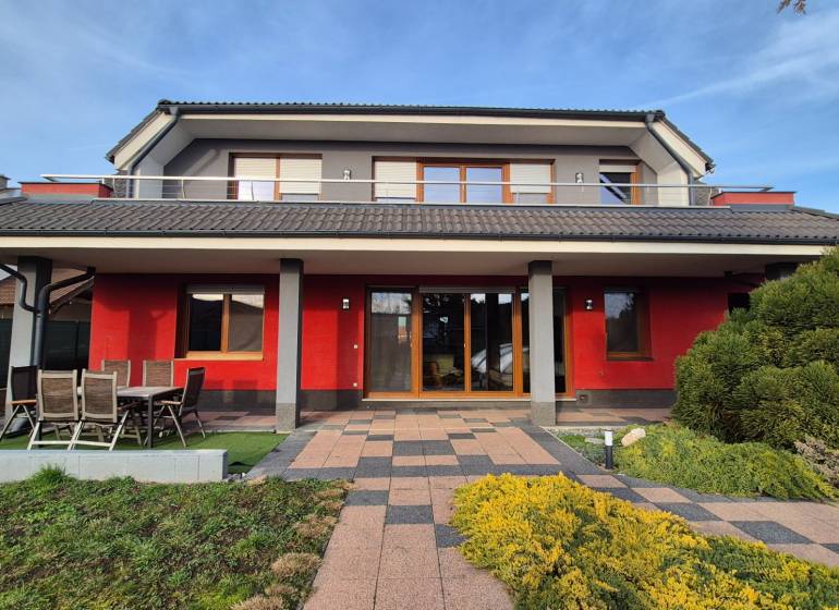 A family house in Krakovany on Vetrná Street, with a red facade and a garden.
