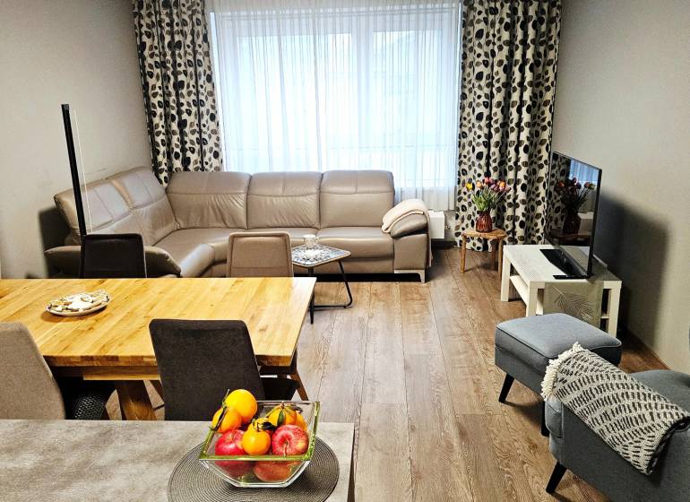 Living room in a 3-room apartment with a leather sofa and a wooden decor floor.