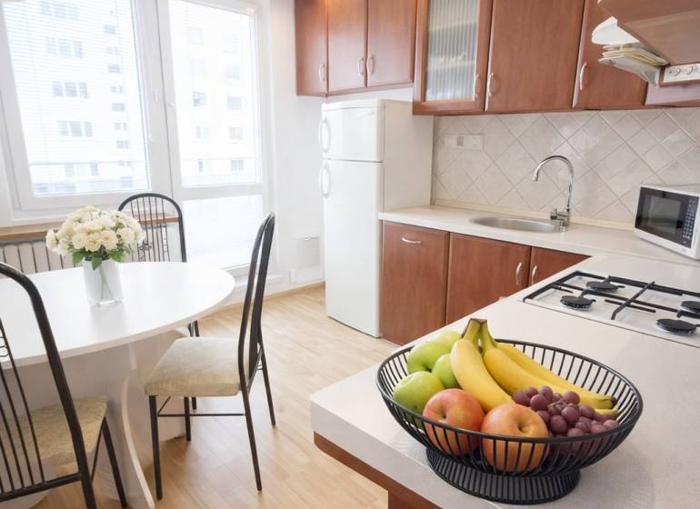 A kitchen in a 3-room apartment with a wooden decor floor and fruit on the table.