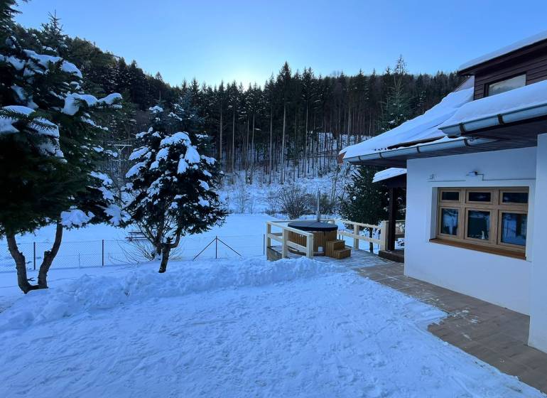 A family house in Bystrá on a snowy street with a view of the forest and snowy landscape.