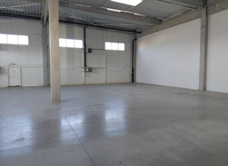 Spacious interior of warehouses and halls with concrete flooring and high ceilings.