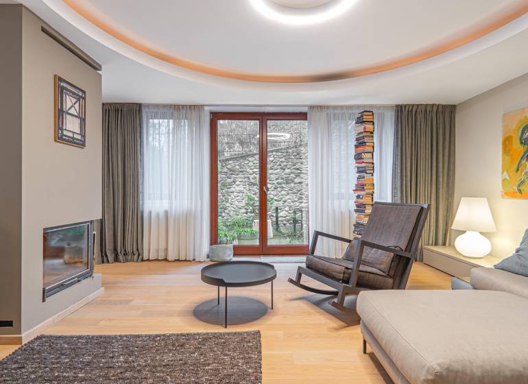 Living room in a 4-room apartment with a wooden decor floor, a fireplace, and a comfortable armchair.