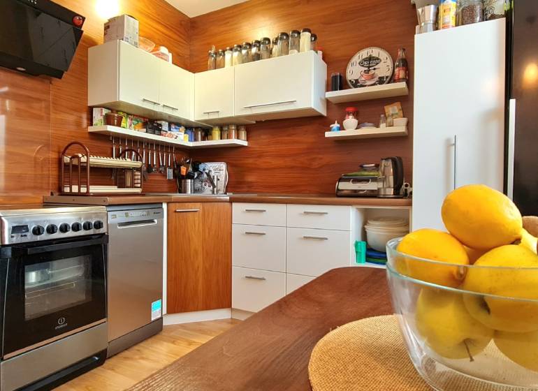 A kitchen in a 2-room apartment with a wood-patterned floor and fruit on the table.