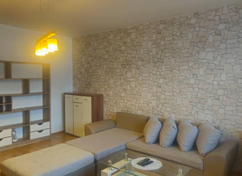 Living room with a stone pattern on the wall, wooden decor flooring, 2-room apartment.