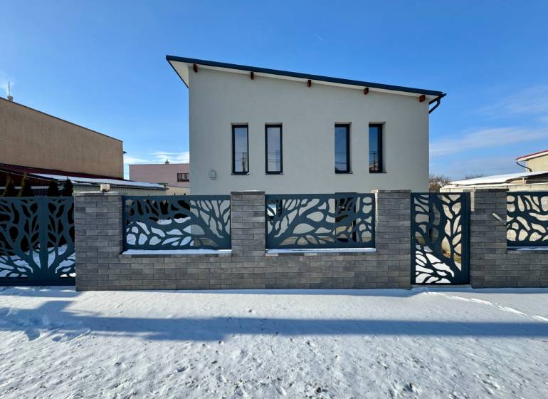 A family house in Čaňa on Gyňovská Street with a modern fence and concrete decor on the snow.
