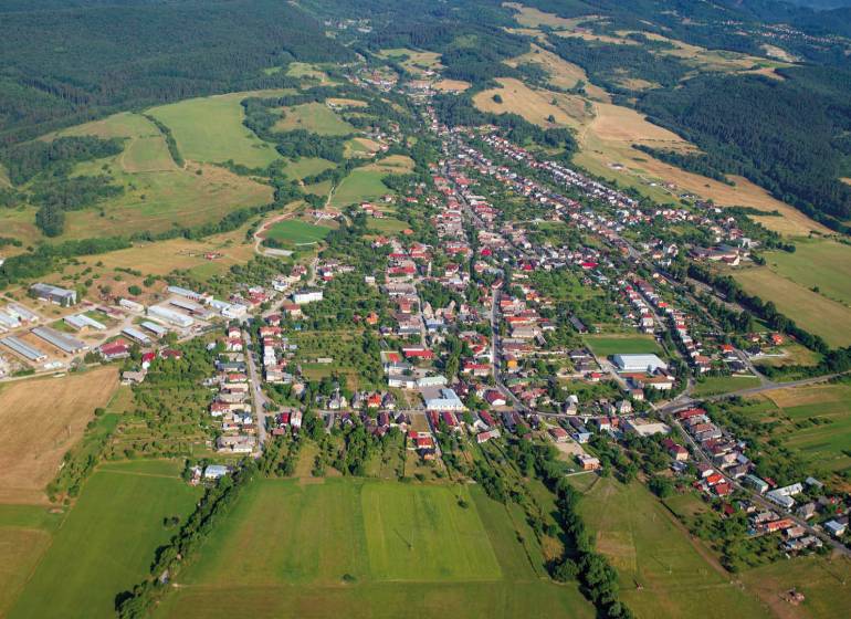Aerial view of agricultural and forest land around Badín, surrounded by houses and buildings.