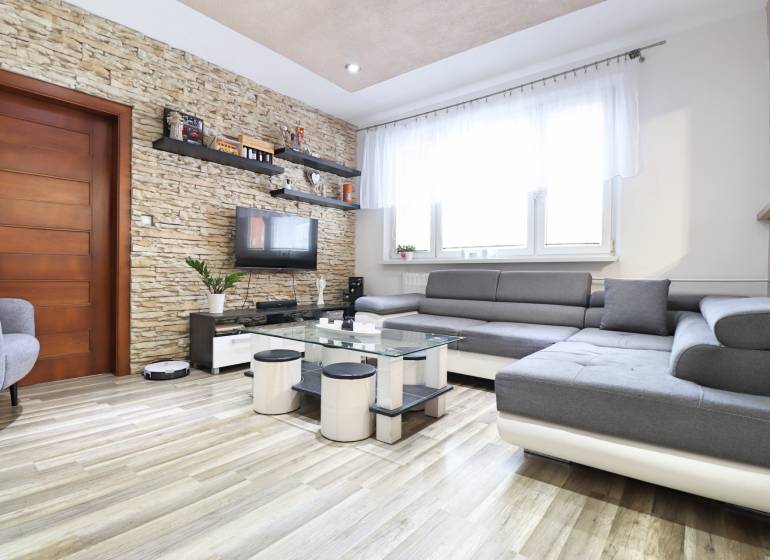 Living room in a 3-room apartment with a wood-decor floor and a stone wall.