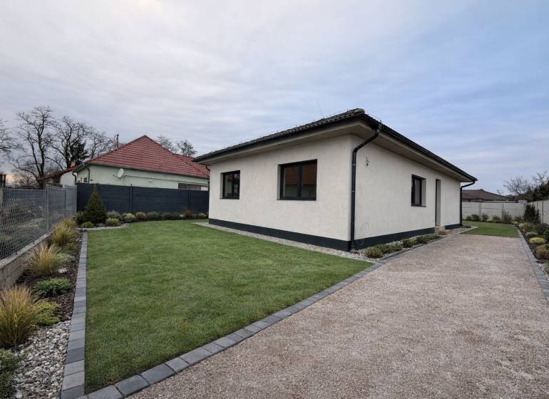 A family house in Veľký Grob with a lawn, gravel path, and landscaped garden.
