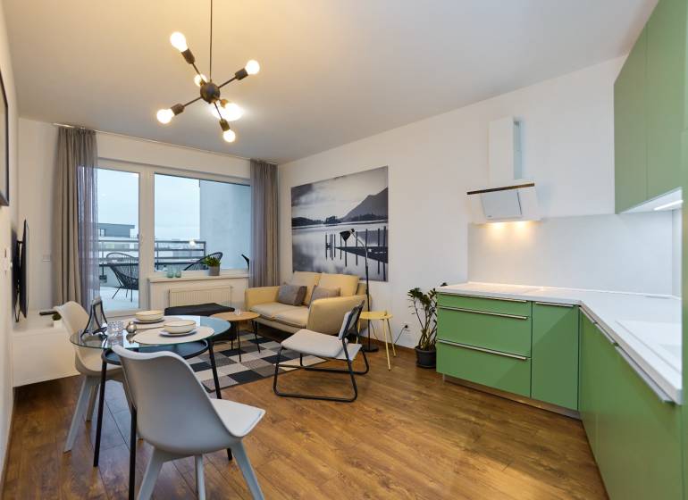 Living room with a kitchenette in a 2-room apartment, floor with wooden decor, green cabinets.