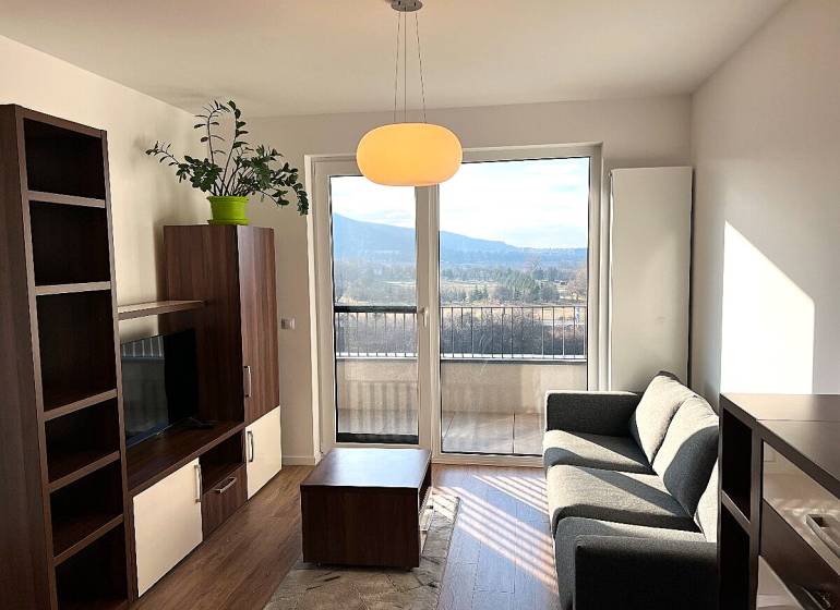 Living room in a two-room apartment with a comfortable sofa and a view from the balcony.
