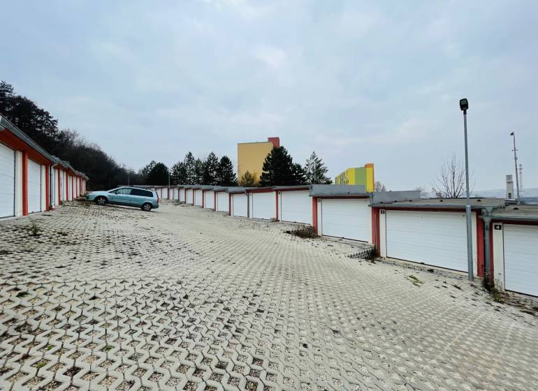 Garages on Rázdolie Street in Malé Uherce with a gravel driveway and a parked car.