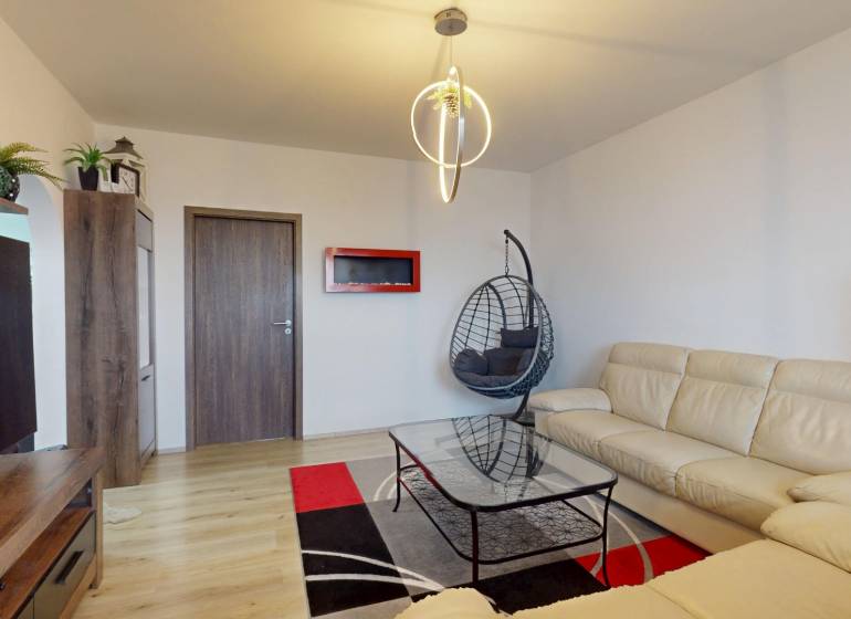 Living room in a 3-room apartment, white sofa, rocking chair, floor with wooden decor.