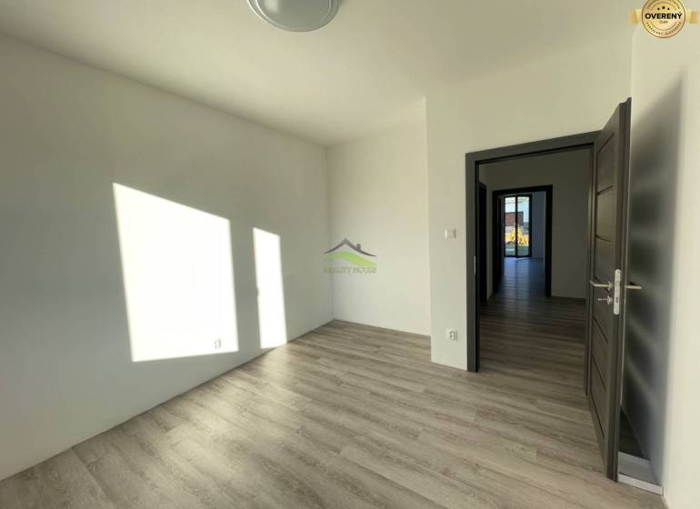 A room with a wooden decor floor in a family house. Light shines through the window.