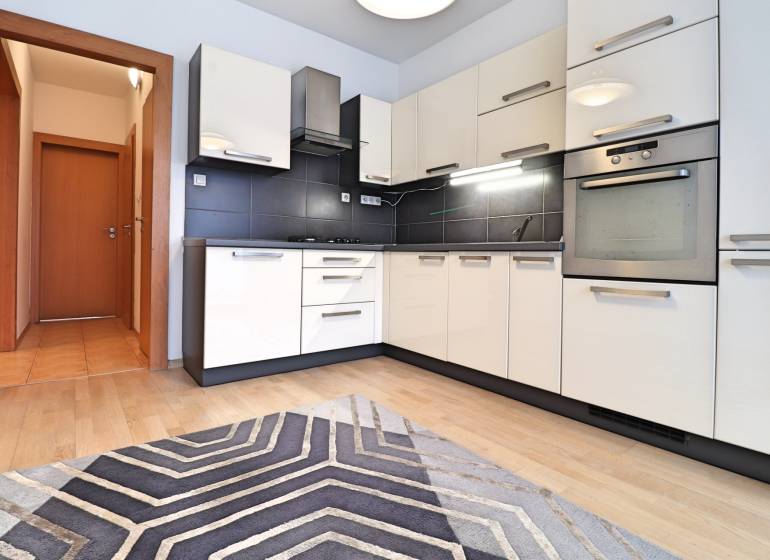 A kitchen unit with black tiles and a floor with a wooden decor in a 3-room apartment.
