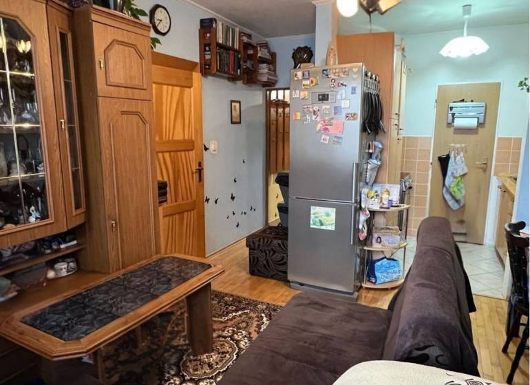 Living room with wood-patterned flooring, seating area, and kitchen.