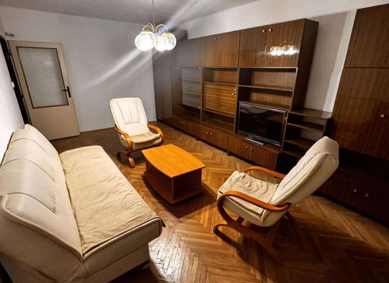 Living room with a sofa, armchairs, furniture, and a wooden decor floor in a two-room apartment.