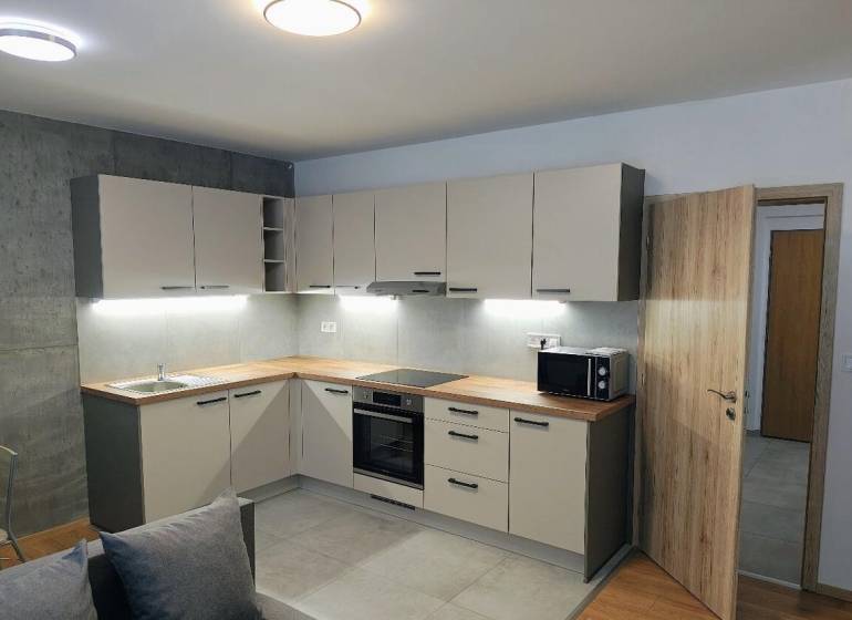 A kitchen in a 3-room apartment with a kitchen unit and a wooden decor floor.