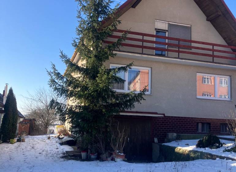 A family house in Rudník, with a gabled roof, trees, and a snowy yard.