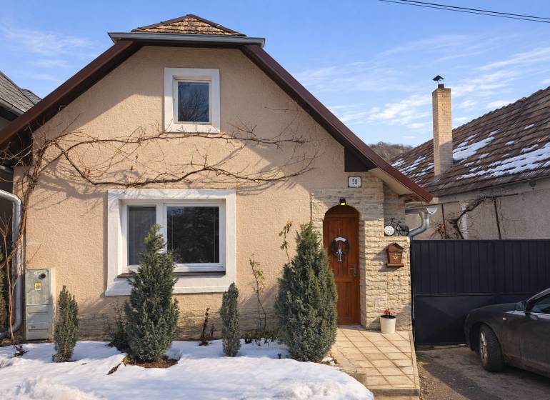 A family house in Sudince with coniferous trees in front of the entrance, a snowy scene.
