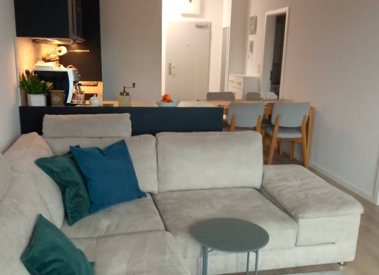 Living room in a two-room apartment with a kitchenette, sofa, and dining table.