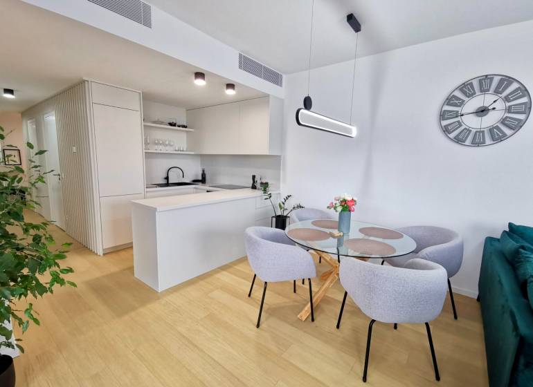 Dining table with chairs in a 3-room apartment, white walls, wooden decor flooring.