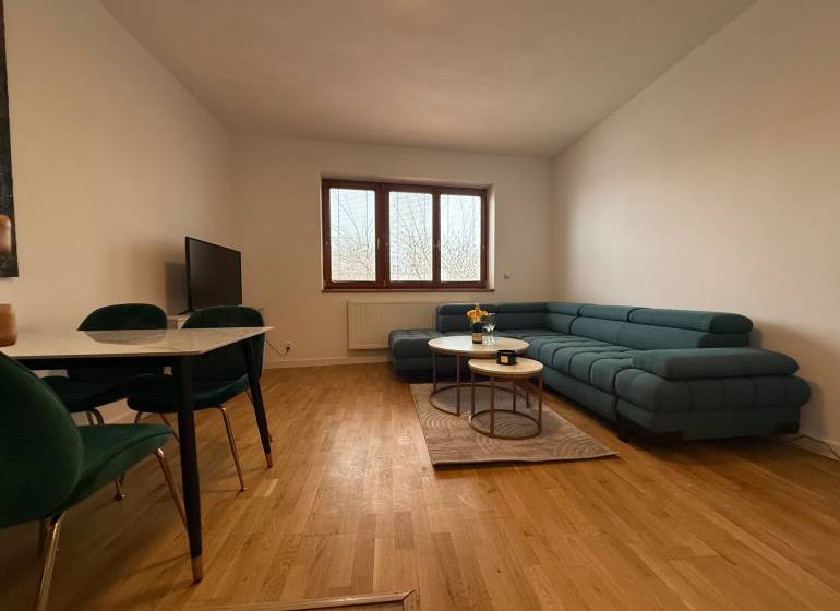 Living room in a family house with a green sofa, dining table, and wooden decor flooring.