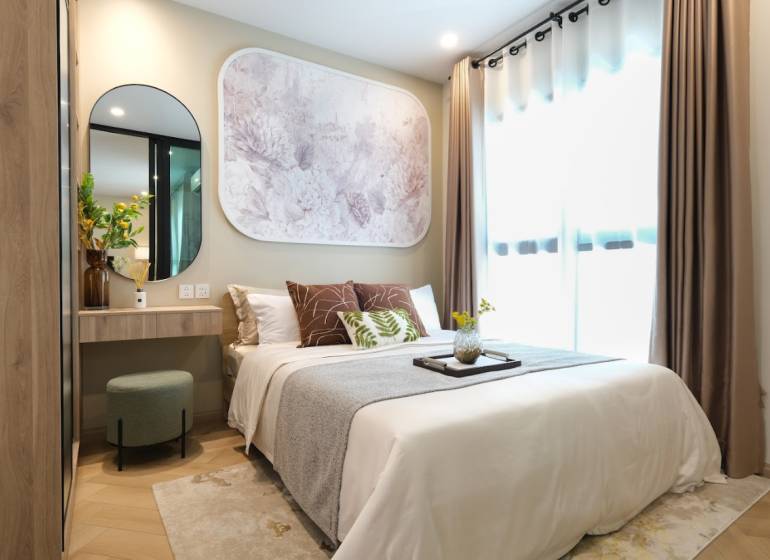 Bedroom in a 2-room apartment with wood-patterned flooring, a mirror, and decorative art.
