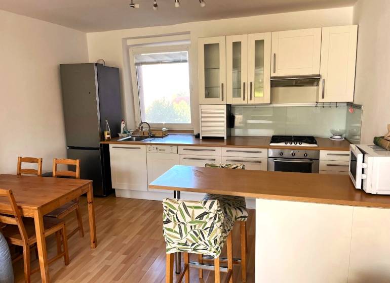 A kitchen in a 3-room apartment with a wooden floor decor and a dining table.