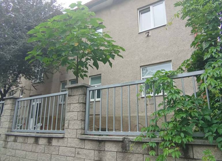The exterior of the house with a stone fence and greenery on Partizánska Street in Lučenec.