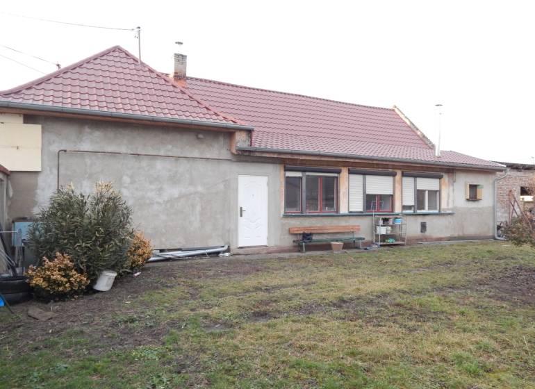 A family house in Kolárovo with a red roof and an unkempt garden.
