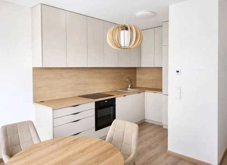 A kitchen in a studio apartment with a wood-patterned floor and a dining table.