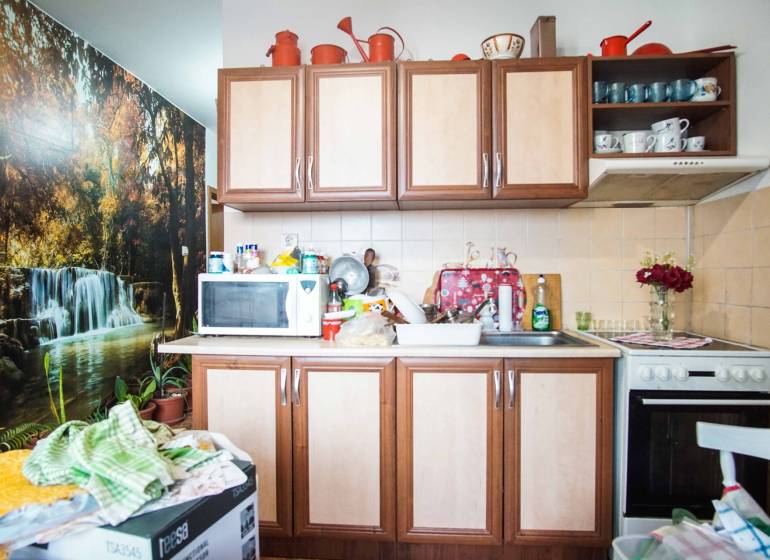 A kitchen in a 2-room apartment with a waterfall wall decoration, cabinets, and appliances.