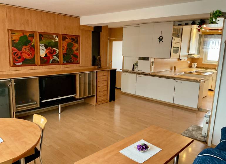 Living room with kitchen in a three-room apartment, wooden decor flooring, painting on the wall.