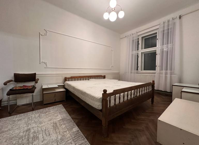 A bedroom in a 3-room apartment with a simple bed and a floor with a wood decor.