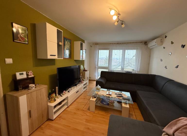 Living room in a three-room apartment with a large sofa and a floor with a wooden decor.