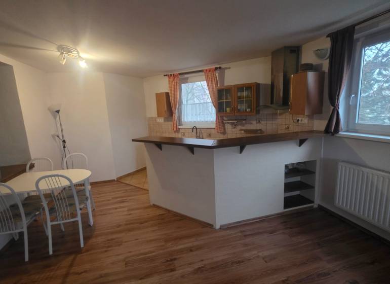 Dining area with wood-patterned flooring in a 3-room apartment, open kitchen with a bar counter.