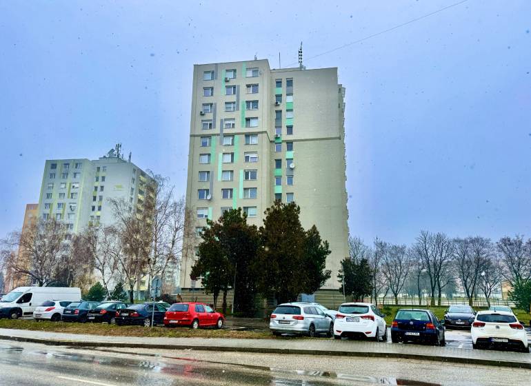 In Nové Zámky on S.H. Vajanský Street, there are tall buildings and parked cars.