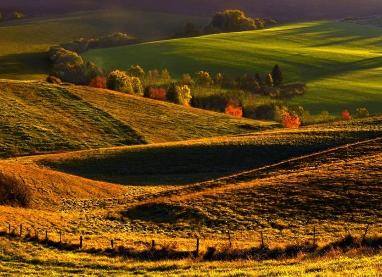 Hilly landscape in the Vráble area with agricultural and forest lands at dusk.