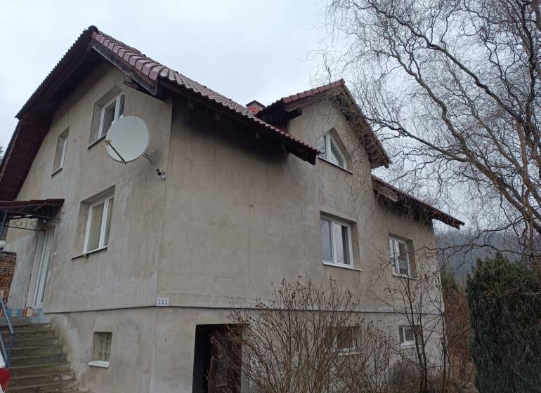 A family house in Orovnica with a light facade, a satellite dish, and a sloped roof.