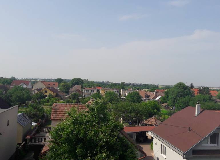 View of family houses in Chorvátsky Grob from Školská Street, with greenery in the background.