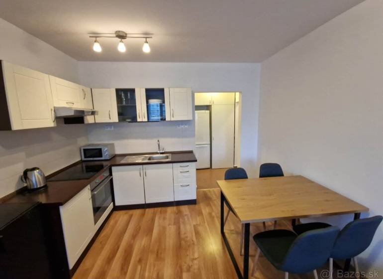 A kitchen in a 2-room apartment with a wooden decor floor, a table with chairs.