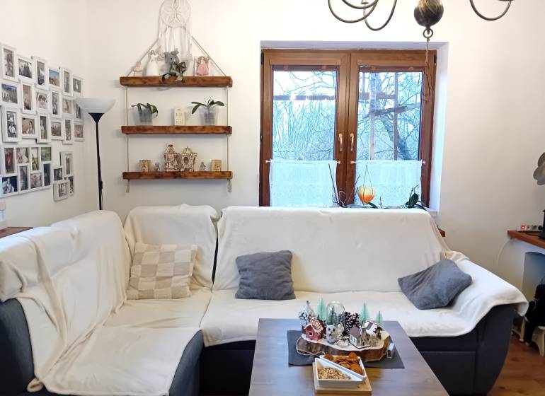 Living room in a family house with a sofa, photo gallery, shelves, and decorations.