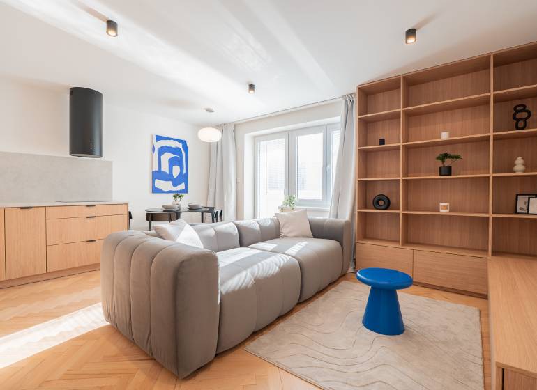 A bright living room in a 3-room apartment with a sofa, wooden decor, and blue accessories.