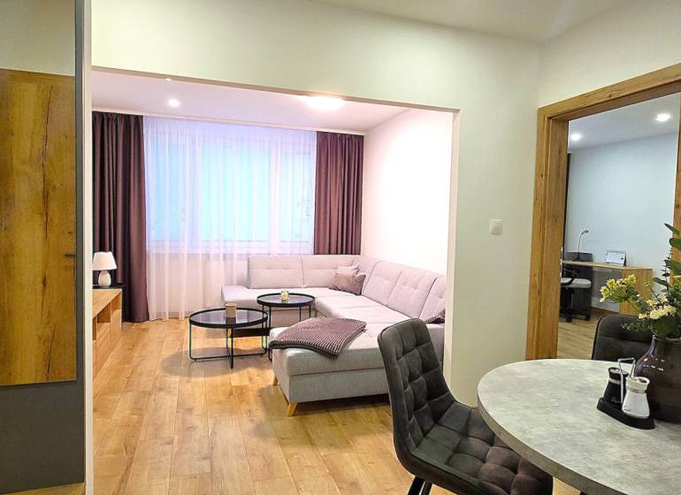 Living room of a three-room apartment with a sofa, table, and floor with a wooden decor.