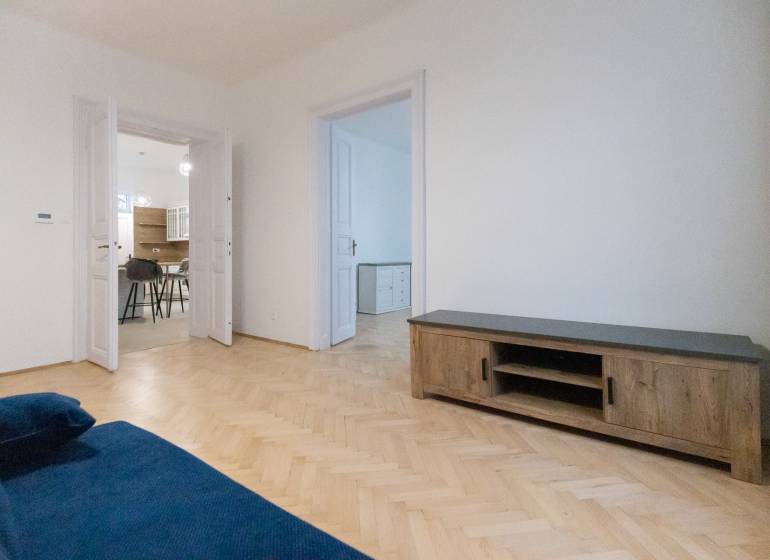 Living room of a three-room apartment with a blue sofa and a wooden decor floor.
