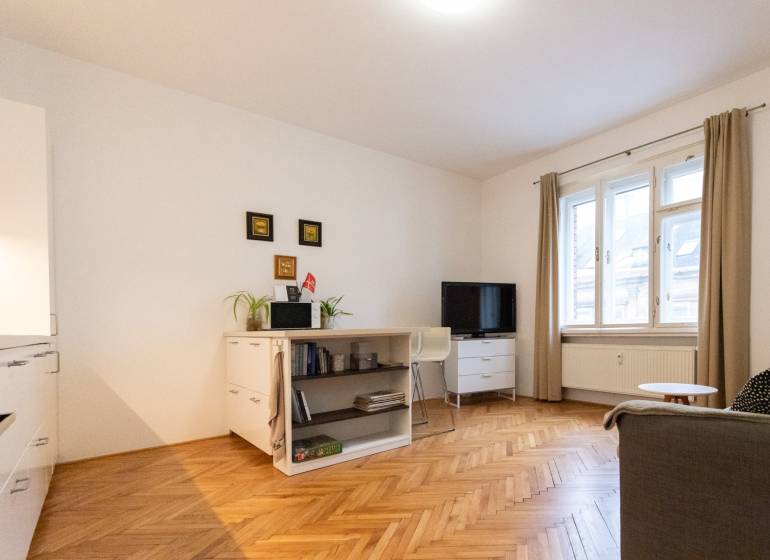 Living room in a two-room apartment with light furniture and a wooden decor floor.