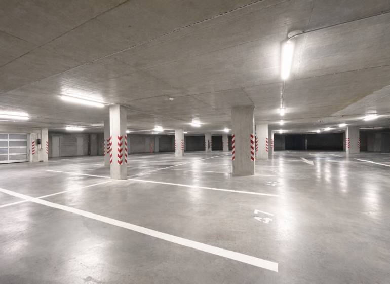 Spacious garages with marked parking spaces, bright lighting, concrete pillars.