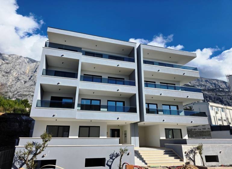 A recreational apartment in Makarska, a building with four floors and balconies, mountain backdrop.