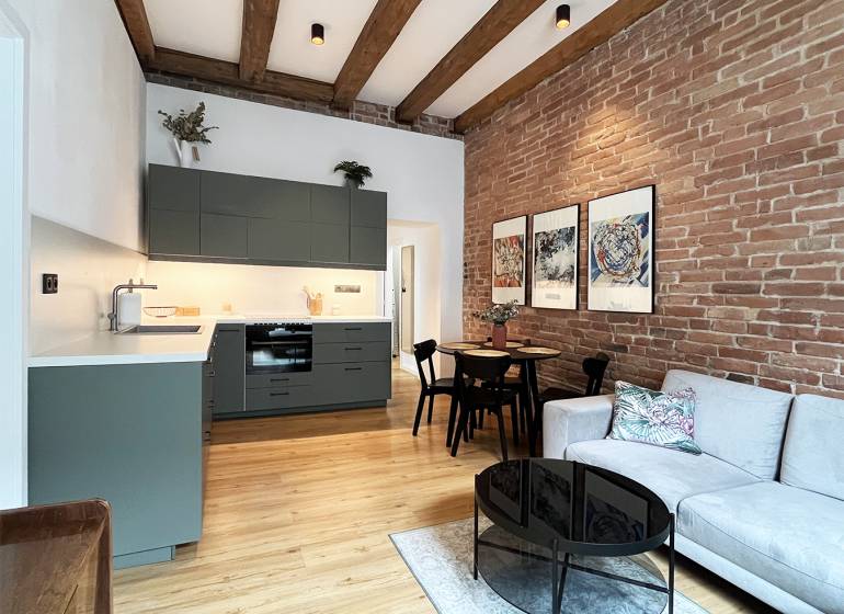 In a 2-room apartment on Vajnorská with a brick wall and modern beams, there is a cozy interior.
