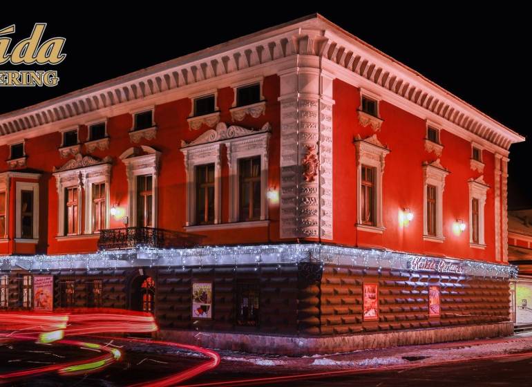 A brightly lit hotel building with a red facade in Poprad. Hotels and guesthouses.
